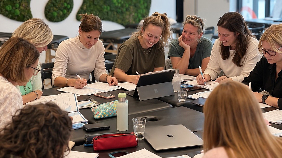 Groep zorgprofessionals bespreekt samen casuïstiek rond vrouwengezondheid in een opleidingsruimte