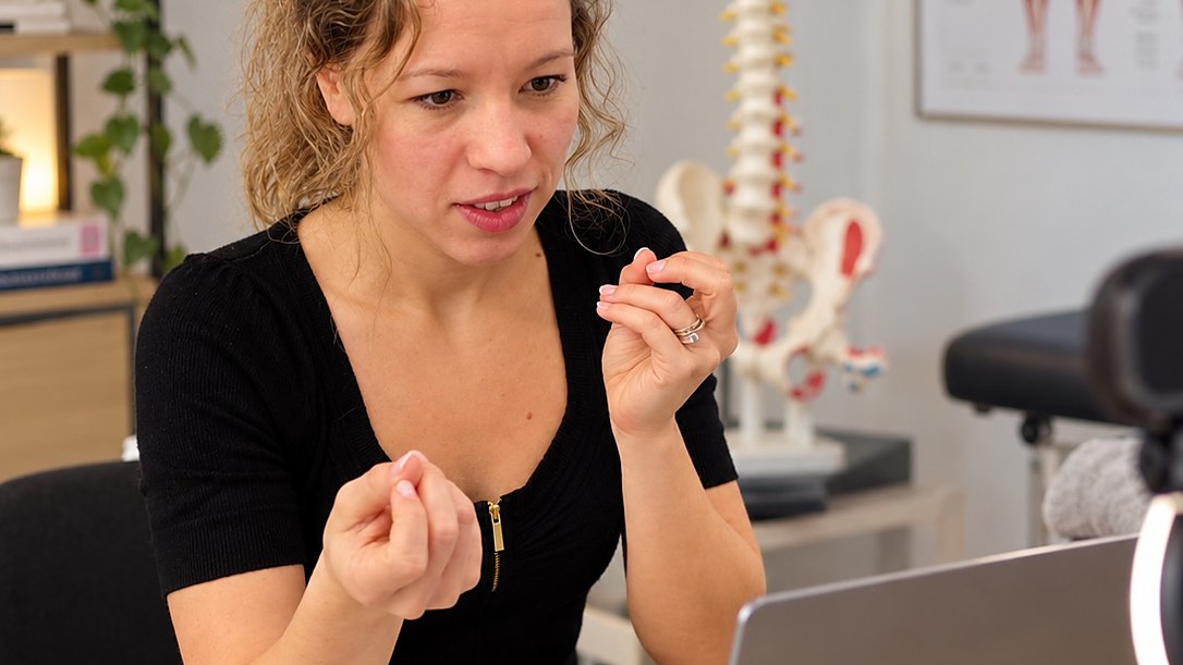 Een zorgprofessional volgt een online opleiding in haar praktijkruimte